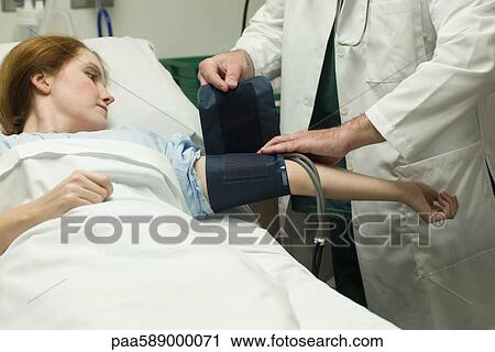 Doctor putting blood pressure cuff on patient in hospital View Large Photo Image Stock Image - Doctor putting blood pressure cuff on patient in hospital. Fotosearch