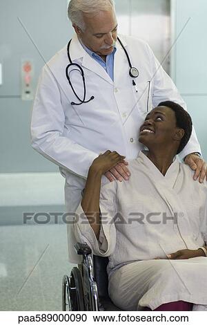 Doctor reassuring female patient in wheelchair View Large Photo Image Stock Image - Doctor reassuring female patient in wheelchair. Fotosearch