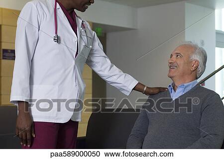 Stock Image - Doctor reassuring patient in waiting room. Fotosearch