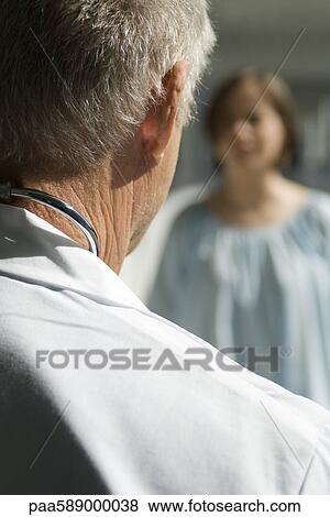 Stock Photo - Doctor talking with patient, over the shoulder view. Fotosearch