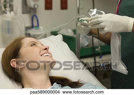 Picture - Female patient smiling as nurse prepares oxygen mask. Fotosearch