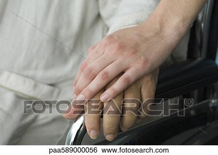 Stock Photograph - Healthcare worker holding patient's hand, cropped. Fotosearch