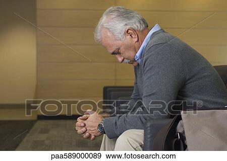 Man sitting in waiting room with head down and hands clasped View Large Photo Image Stock Photo - Man sitting in waiting room with head down and hands clasped. Fotosearch
