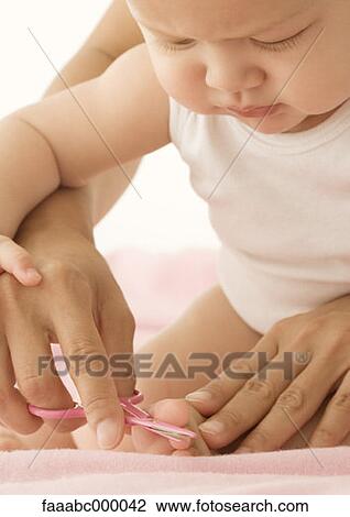 Stock Image - baby, toddler, infant, cutting, nail scissors, childhood, infancy. Fotosearch