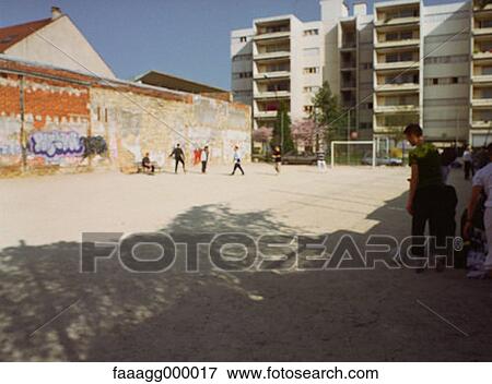 Stock Photo - young, young people, soccer field, soccer grounds, building, buildings, urban. Fotosearch
