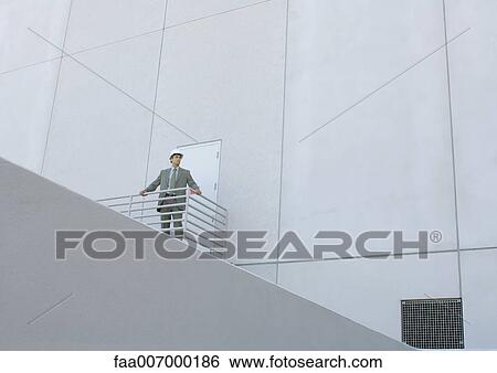 Stock Photograph - Achitect standing next to building, low angle view. Fotosearch