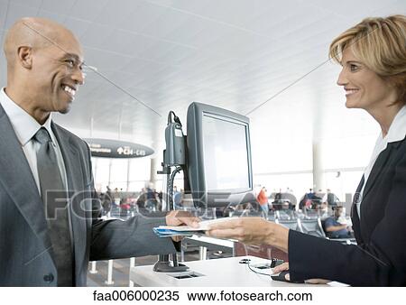 Airline attendant handing passenger ticket at check-in counter View Large Photo Image Stock Photography - Airline attendant handing passenger ticket at check-in counter. Fotosearch
