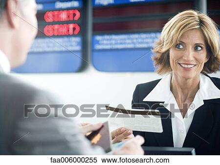 Airline attendant handing passenger ticket at check-in counter View Large Photo Image Stock Photography - Airline attendant handing passenger ticket at check-in counter. Fotosearch