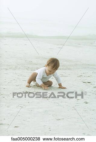 Baby sitting on beach, touching sand View Large Photo Image Stock Photo - Baby sitting on beach, touching sand. Fotosearch