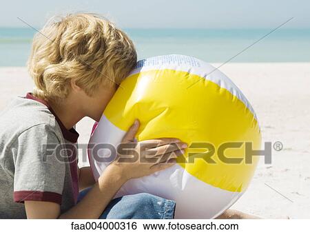 Boy blowing up beach ball View Large Photo Image Stock Photograph - Boy blowing up beach ball. Fotosearch