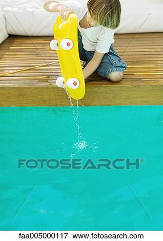 Boy holding dripping skateboard over edge of pool View Large Photo Image Stock Photo - Boy holding dripping skateboard over edge of pool. Fotosearch