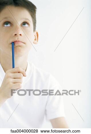Boy holding pencil to mouth, looking up View Large Photo Image Stock Photo - Boy holding pencil to mouth, looking up. Fotosearch