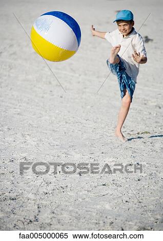 Stock Photography - Boy kicking beach ball. Fotosearch
