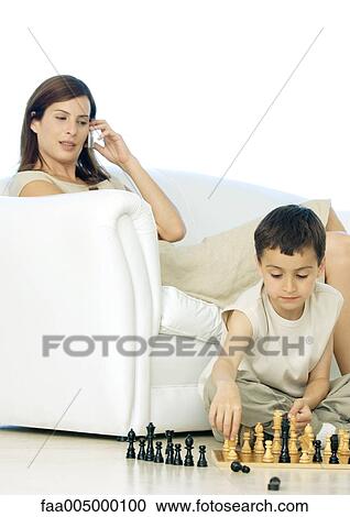 Boy playing with chess game while mother uses cell phone View Large Photo Image Stock Image - Boy playing with chess game while mother uses cell phone. Fotosearch