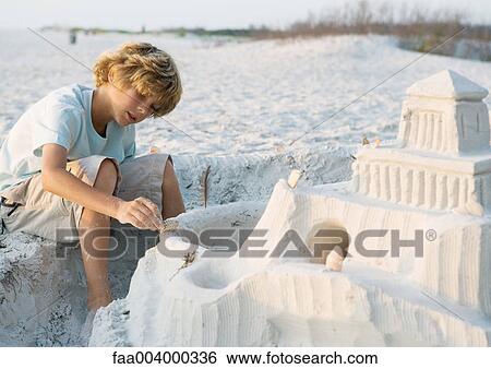 Boy putting finishing touches on sand castle View Large Photo Image Stock Photograph - Boy putting finishing touches on sand castle. Fotosearch