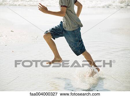 Stock Photo - Boy running in surf on beach. Fotosearch