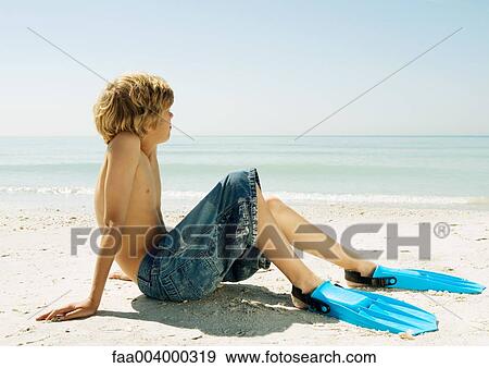 Boy sitting on beach, wearing flippers View Large Photo Image Stock Photo - Boy sitting on beach, wearing flippers. Fotosearch
