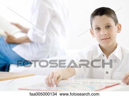 Boy sitting with game board View Large Photo Image Picture - Boy sitting with game board. Fotosearch