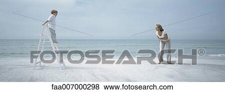 Stock Photo - Boy standing on ladder on beach looking at mother. Fotosearch