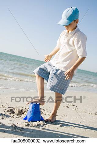 Boy stepping on sand bucket on beach View Large Photo Image Stock Image - Boy stepping on sand bucket on beach. Fotosearch