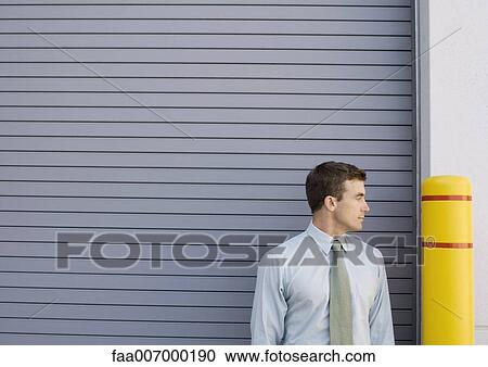 Business man looking at yellow post View Large Photo Image Stock Image - Business man looking at yellow post. Fotosearch