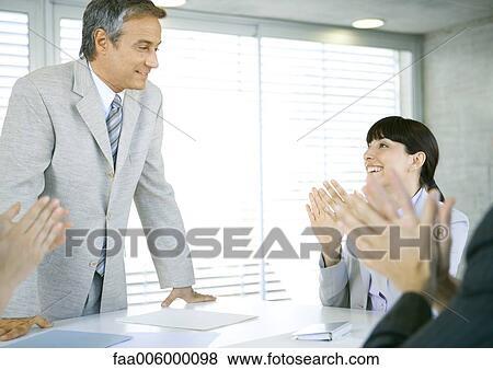 Stock Photo - Business team applauding colleague in conference room. Fotosearch