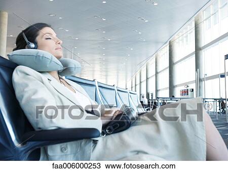 Business traveler sitting in airport lounge, napping with neck pillow View Large Photo Image Stock Image - Business traveler sitting in airport lounge, napping with neck pillow. Fotosearch