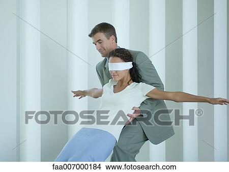 Picture - Businessman catching blindfolded woman. Fotosearch