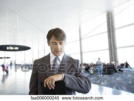 Businessman checking watch in airport View Large Photo Image Stock Photography - Businessman checking watch in airport. Fotosearch