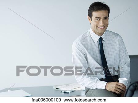 Businessman in office, holding cup and smiling at camera View Large Photo Image Stock Photo - Businessman in office, holding cup and smiling at camera. Fotosearch