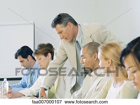Businessman leaning over colleague's shoulder during meeting View Large Photo Image Stock Photo - Businessman leaning over colleague's shoulder during meeting. Fotosearch