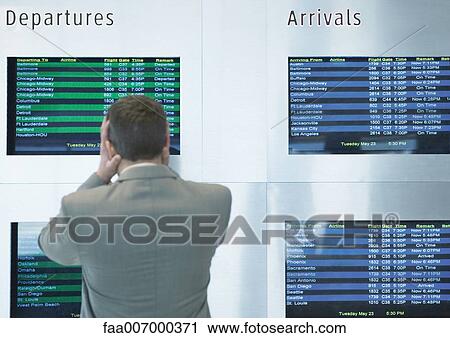 Businessman looking at departure board, holding head, rear view View Large Photo Image Stock Image - Businessman looking at departure board, holding head, rear view. Fotosearch