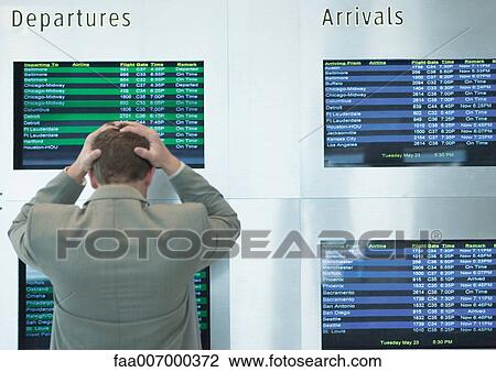 Businessman looking at departure board, holding head, rear view View Large Photo Image Stock Image - Businessman looking at departure board, holding head, rear view. Fotosearch