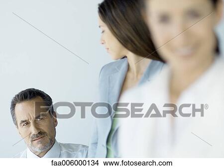 Businessman looking suspiciously at female colleague View Large Photo Image Picture - Businessman looking suspiciously at female colleague. Fotosearch