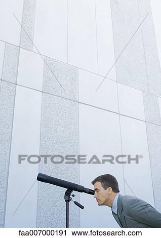 Stock Image - Businessman looking through telescope. Fotosearch