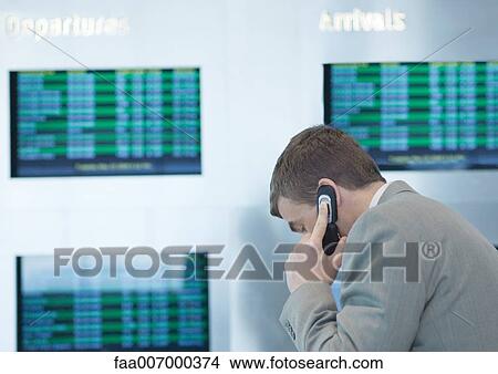 Businessman phoning in front of departure board View Large Photo Image Picture - Businessman phoning in front of departure board. Fotosearch