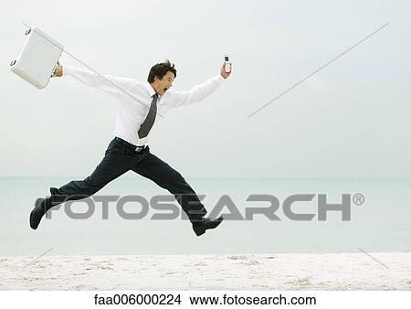 Businessman running and jumping on beach View Large Photo Image Picture - Businessman running and jumping on beach. Fotosearch