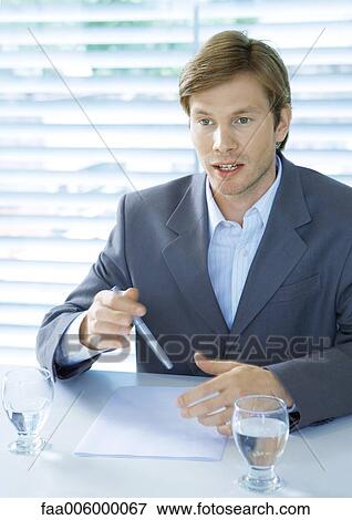 Businessman sitting at desk speaking and gesturing View Large Photo Image Stock Photo - Businessman sitting at desk speaking and gesturing. Fotosearch