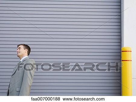 Stock Photo - Businessman standing and smiling, leaning backwards with eyes shut. Fotosearch
