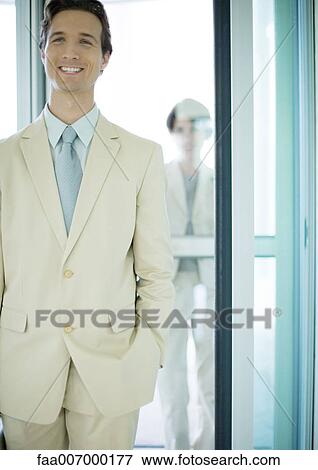 Businessman standing in entrance, smiling View Large Photo Image Stock Photo - Businessman standing in entrance, smiling. Fotosearch