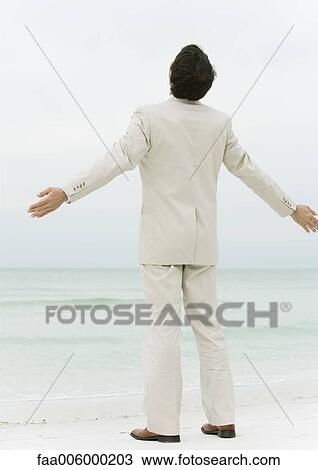 Businessman standing on beach with arms out, rear view View Large Photo Image Stock Image - Businessman standing on beach with arms out, rear view. Fotosearch
