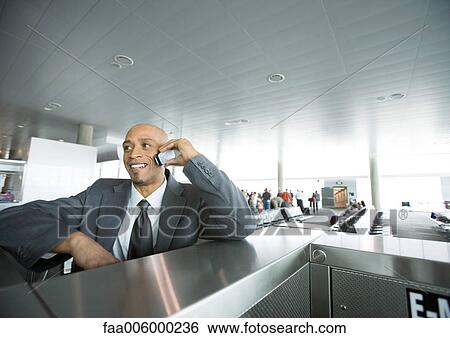 Businessman using cell phone in airport lounge area View Large Photo Image Stock Photograph - Businessman using cell phone in airport lounge area. Fotosearch