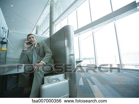 Businessman using pay phone in airport View Large Photo Image Stock Photograph - Businessman using pay phone in airport. Fotosearch