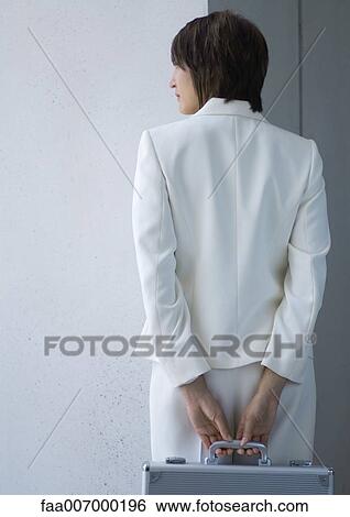 Businesswoman holding briefcase behind back, rear view View Large Photo Image Stock Photograph - Businesswoman holding briefcase behind back, rear view. Fotosearch