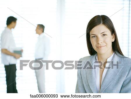 Businesswoman looking at camera, colleagues in background View Large Photo Image Stock Image - Businesswoman looking at camera, colleagues in background. Fotosearch