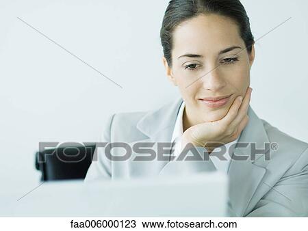 Businesswoman smiling as she works at computer View Large Photo Image Stock Image - Businesswoman smiling as she works at computer. Fotosearch