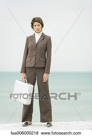 Businesswoman standing on beach holding briefcase View Large Photo Image Stock Photo - Businesswoman standing on beach holding briefcase. Fotosearch