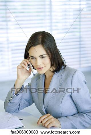Businesswoman using cell phone at desk View Large Photo Image Stock Image - Businesswoman using cell phone at desk. Fotosearch