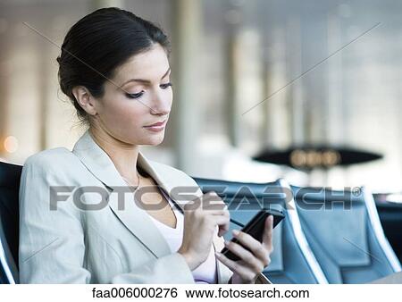 Businesswoman using electronic organizer in airport lounge area View Large Photo Image Stock Photograph - Businesswoman using electronic organizer in airport lounge area. Fotosearch