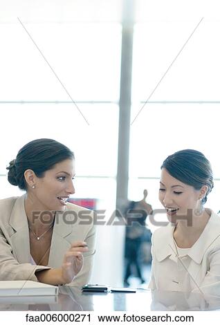 Businesswomen talking, one looking at electronic organizer View Large Photo Image Stock Image - Businesswomen talking, one looking at electronic organizer. Fotosearch